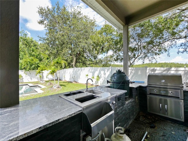 view of patio / terrace with area for grilling, a fenced in pool, and sink