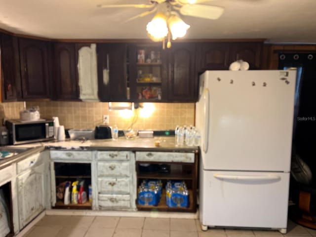 kitchen with decorative backsplash, light tile patterned floors, white refrigerator, and dark brown cabinetry