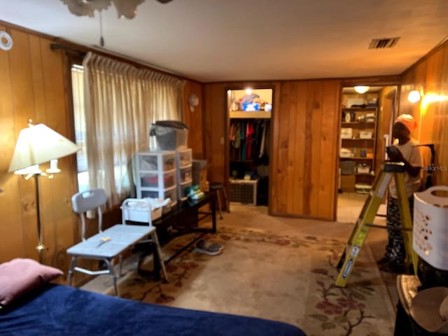 bedroom featuring light carpet and wooden walls