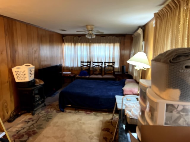 bedroom with ceiling fan and wood walls