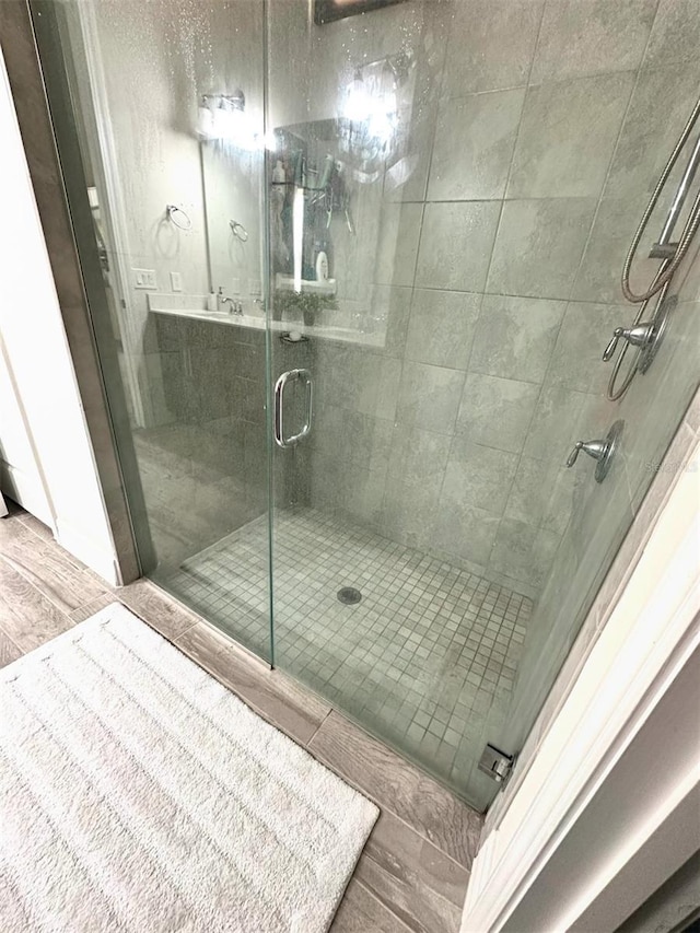 bathroom with wood-type flooring, vanity, and an enclosed shower