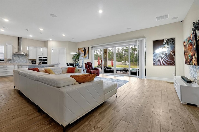 living room with light wood-style flooring, recessed lighting, visible vents, and baseboards