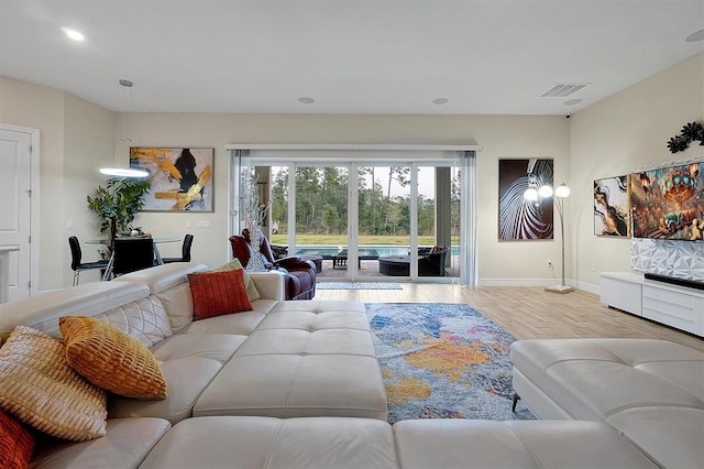 living area featuring visible vents, baseboards, and wood finished floors