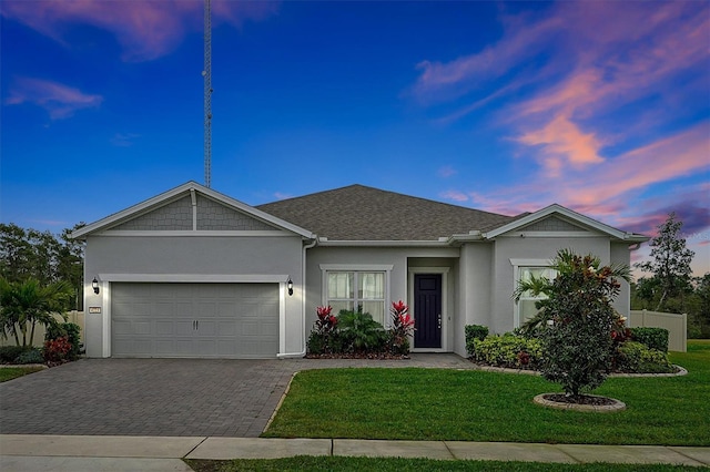 ranch-style house with decorative driveway, an attached garage, a lawn, and stucco siding