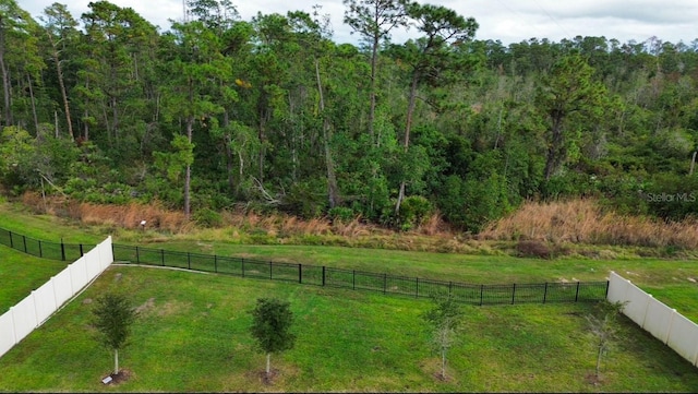 view of yard with a wooded view and a fenced backyard