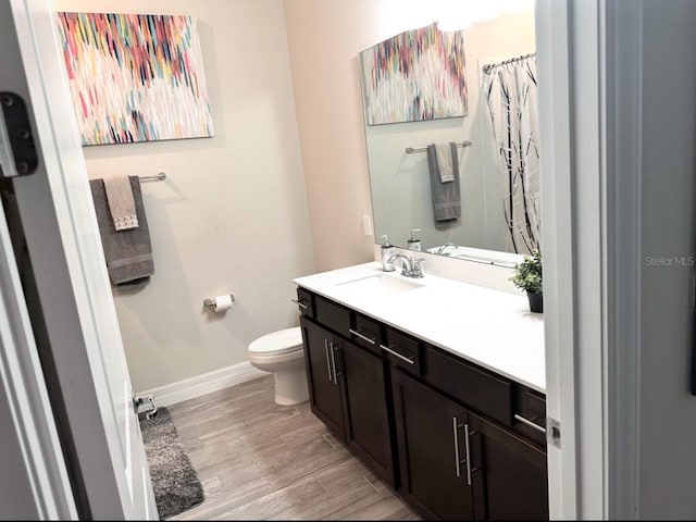 full bathroom featuring toilet, curtained shower, wood finished floors, baseboards, and vanity