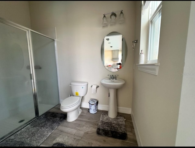 bathroom with wood finished floors, baseboards, a stall shower, a sink, and toilet