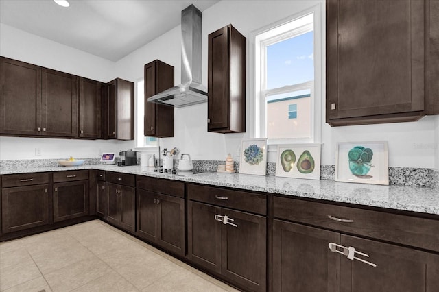 kitchen featuring light stone counters, dark brown cabinets, wall chimney exhaust hood, and black cooktop