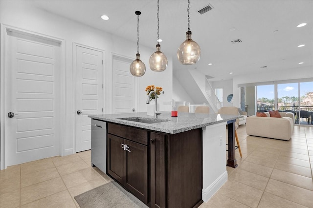 kitchen with light stone countertops, sink, light tile patterned floors, and an island with sink