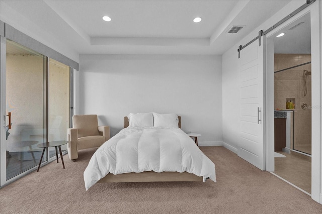 carpeted bedroom with a barn door and a tray ceiling