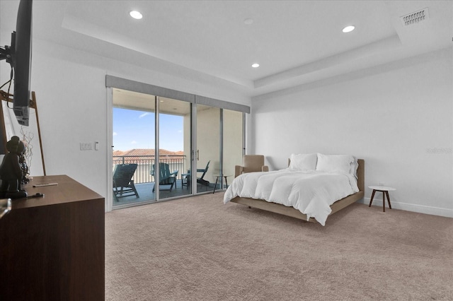 carpeted bedroom with access to outside and a tray ceiling