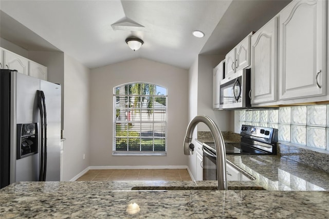 kitchen featuring vaulted ceiling, stainless steel appliances, white cabinets, and stone countertops