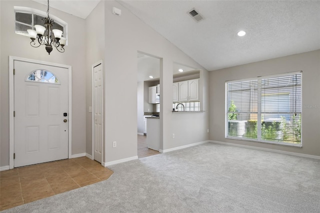 entrance foyer featuring a textured ceiling, vaulted ceiling, light carpet, and a notable chandelier