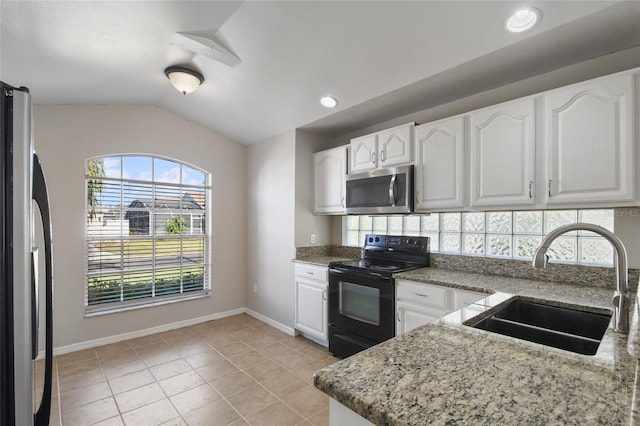 kitchen featuring appliances with stainless steel finishes, lofted ceiling, sink, white cabinets, and light stone counters