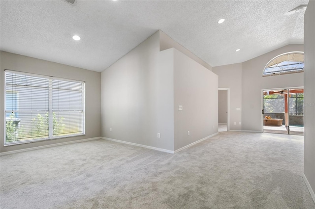 empty room featuring vaulted ceiling, light colored carpet, and a textured ceiling