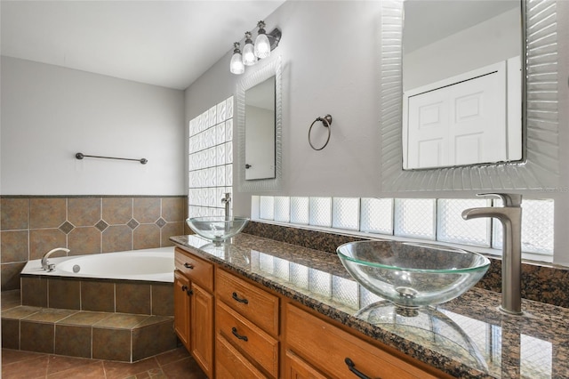 bathroom featuring a relaxing tiled tub, tile patterned floors, and vanity