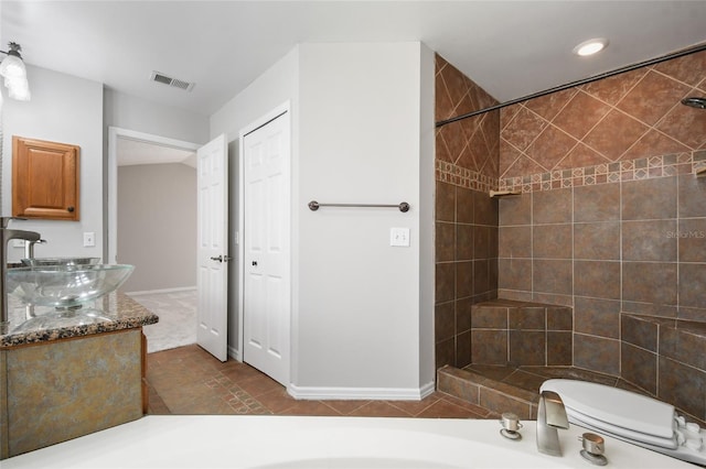 bathroom with vanity, tile patterned floors, toilet, and tiled shower