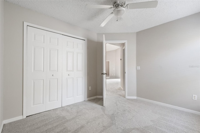 unfurnished bedroom with ceiling fan, light colored carpet, a closet, and a textured ceiling