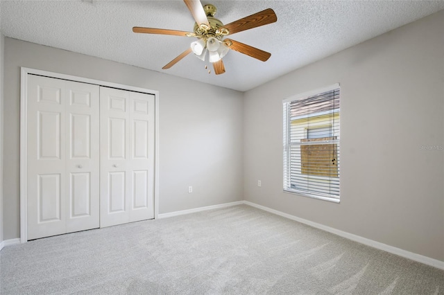 unfurnished bedroom featuring ceiling fan, light carpet, a closet, and a textured ceiling