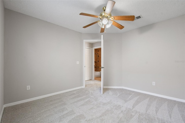 spare room featuring ceiling fan, light colored carpet, and a textured ceiling