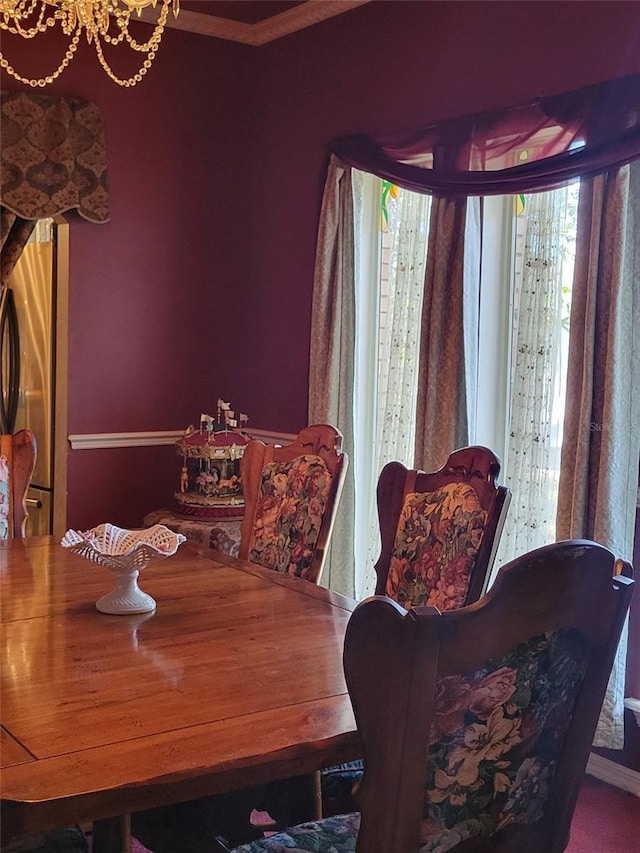 dining area with a notable chandelier, crown molding, and a healthy amount of sunlight