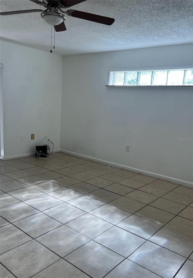 tiled empty room with ceiling fan and a textured ceiling