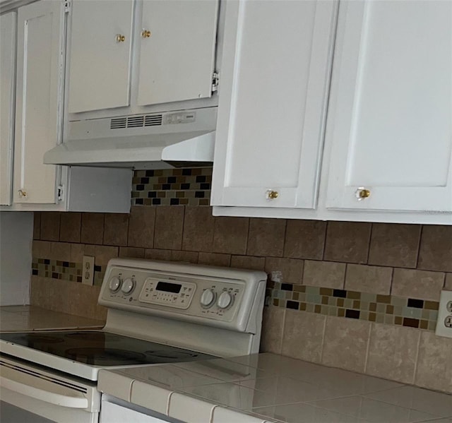 kitchen featuring white cabinets, decorative backsplash, and white electric range