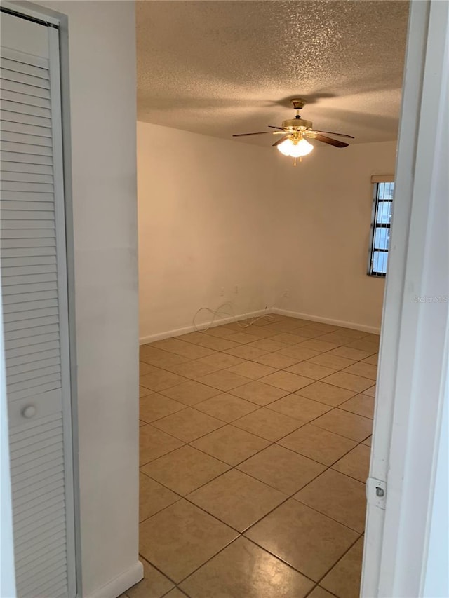 unfurnished room with ceiling fan, light tile patterned flooring, and a textured ceiling