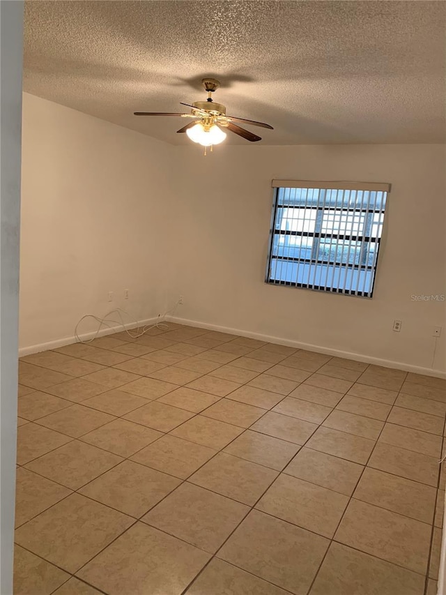 spare room featuring ceiling fan, light tile patterned floors, and a textured ceiling