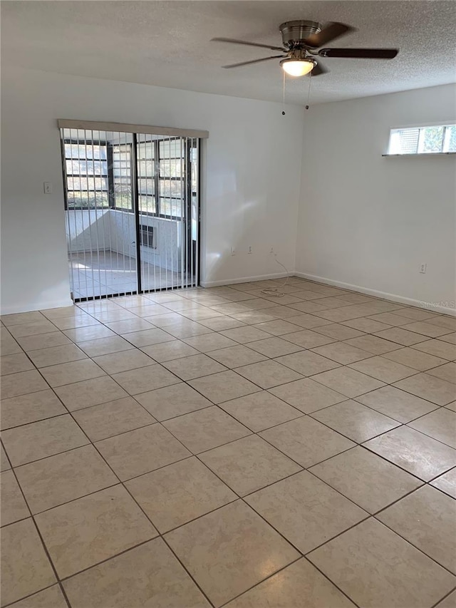 empty room featuring ceiling fan, light tile patterned flooring, and a textured ceiling