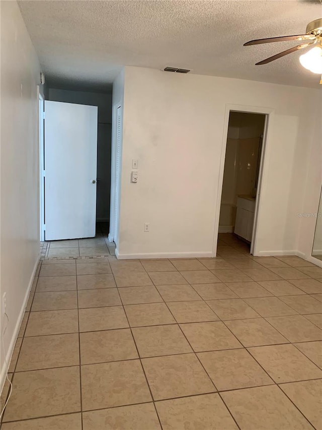 tiled empty room with a textured ceiling and ceiling fan