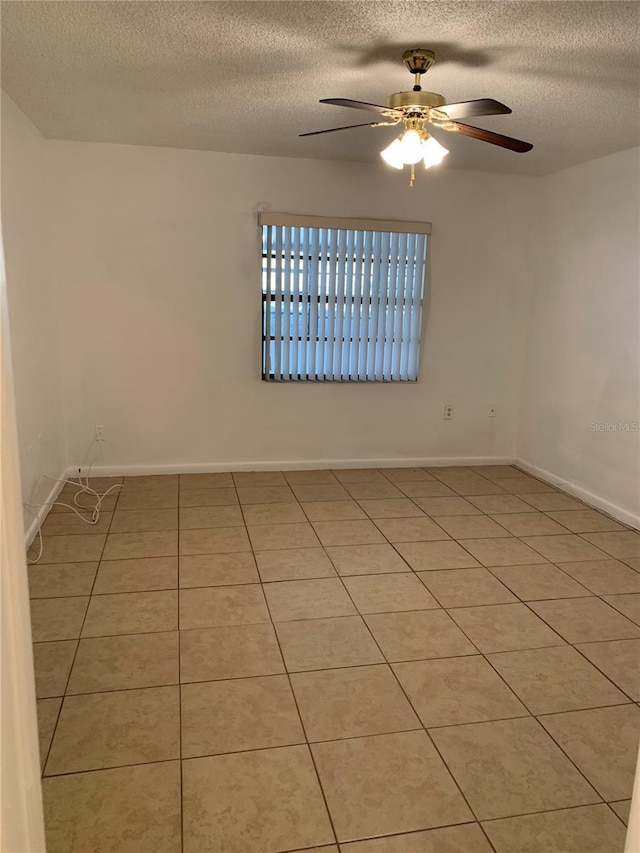 empty room with light tile patterned floors, a textured ceiling, and ceiling fan