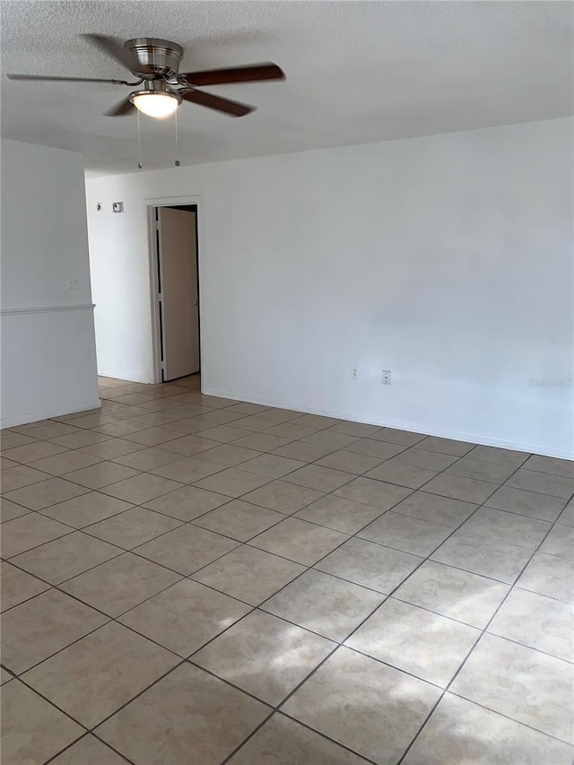 tiled spare room with a textured ceiling and ceiling fan