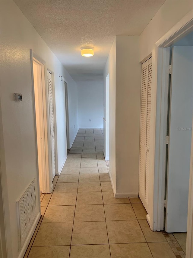 corridor featuring light tile patterned floors and a textured ceiling