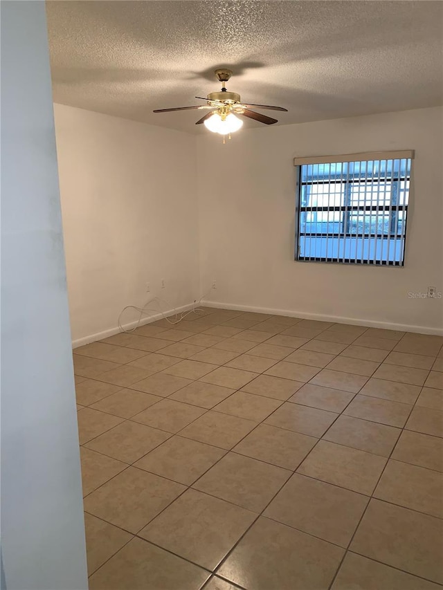 empty room with a textured ceiling, ceiling fan, and light tile patterned flooring