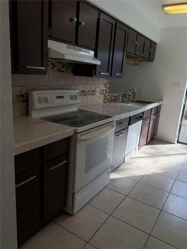 kitchen with backsplash, white appliances, dark brown cabinetry, sink, and light tile patterned floors