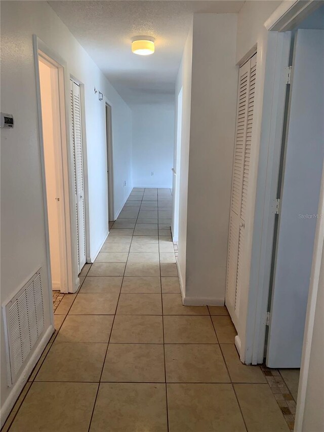 hall with light tile patterned floors and a textured ceiling