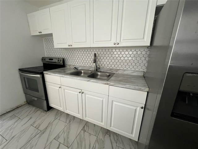 kitchen featuring decorative backsplash, appliances with stainless steel finishes, white cabinetry, and sink