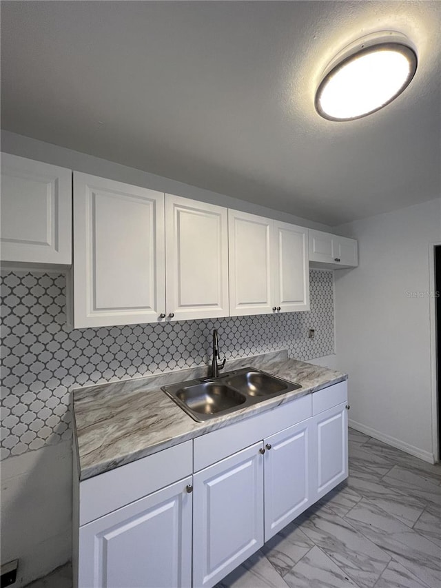 kitchen with decorative backsplash, white cabinetry, and sink