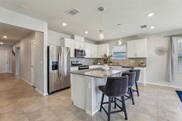 kitchen featuring appliances with stainless steel finishes, a kitchen island, visible vents, and white cabinetry