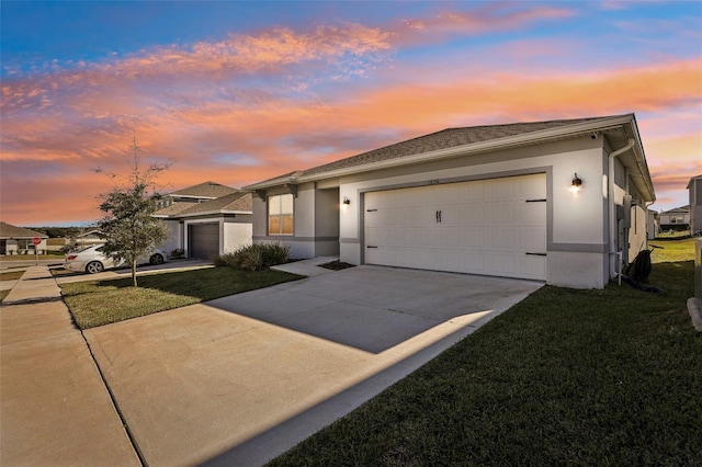 view of front of home featuring an attached garage, driveway, a front lawn, and stucco siding