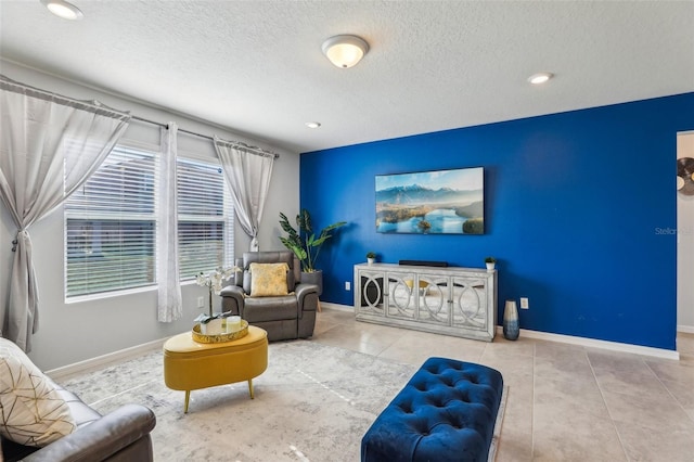 tiled living area with a textured ceiling and baseboards