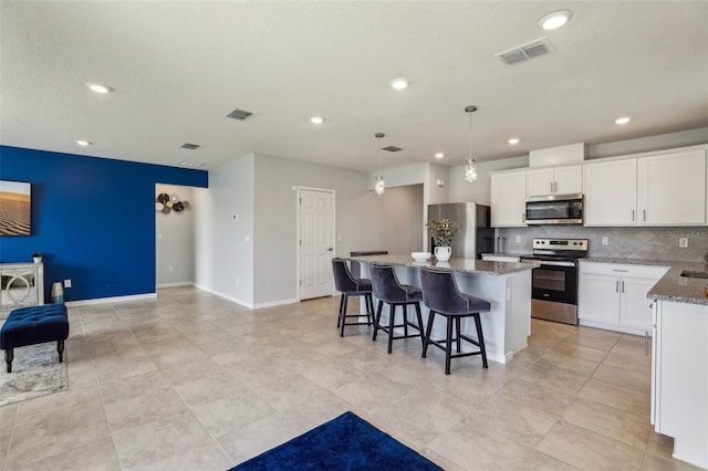 kitchen with tasteful backsplash, visible vents, a kitchen island, appliances with stainless steel finishes, and white cabinetry