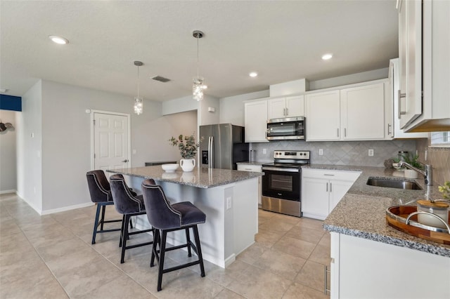 kitchen with white cabinets, sink, a kitchen island, and appliances with stainless steel finishes