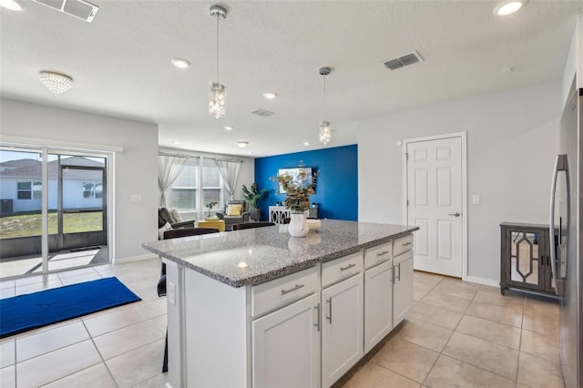 kitchen featuring freestanding refrigerator, white cabinets, visible vents, and light tile patterned flooring