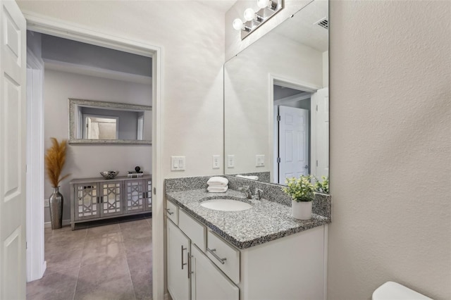 bathroom featuring toilet, tile patterned flooring, and vanity