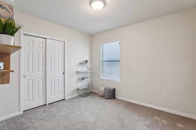 unfurnished bedroom featuring a textured ceiling, a closet, carpet flooring, and baseboards