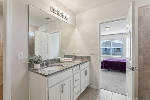 bathroom with double vanity, tile patterned flooring, a sink, and baseboards