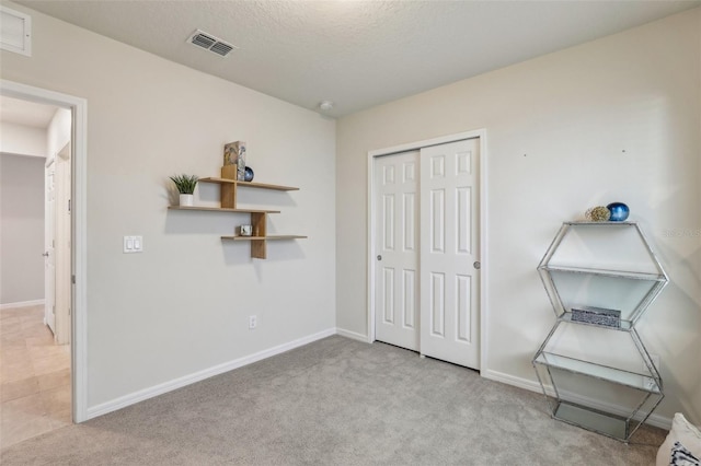 unfurnished bedroom featuring carpet floors, a closet, visible vents, and baseboards