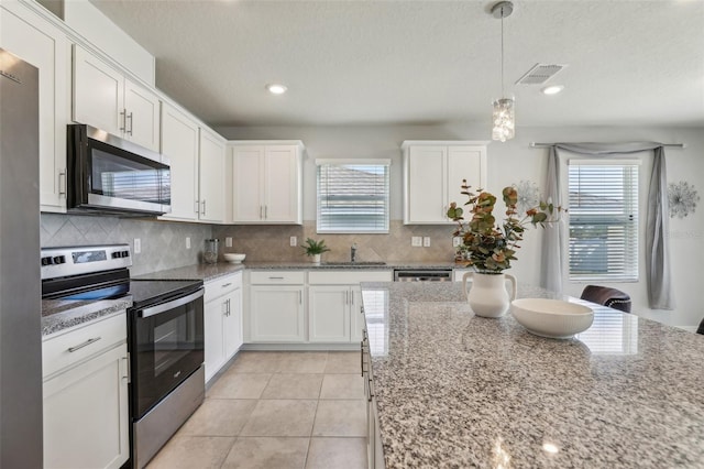 kitchen featuring appliances with stainless steel finishes, a healthy amount of sunlight, light tile patterned flooring, and white cabinetry